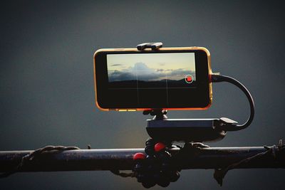 Close-up of camera phone against sky