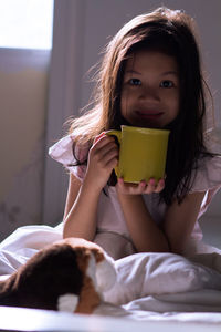 Portrait of cute girl holding while relaxing on bed at home