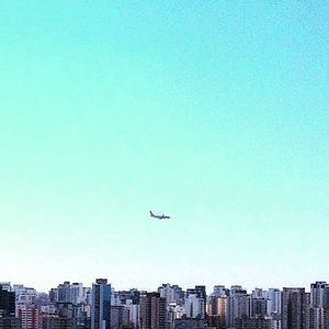 Low angle view of airplane flying in city against clear sky