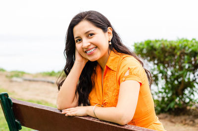 Portrait of smiling young woman against sky