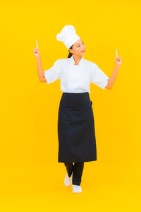 Full length of a woman standing against yellow background