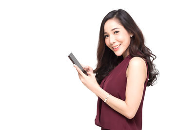 Portrait of young woman using phone against white background