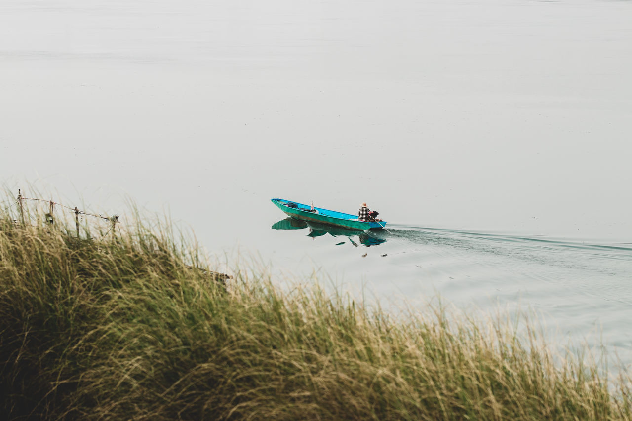 SIDE VIEW OF MAN IN BOAT ON SEA