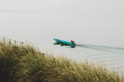 Side view of man on boat at shore against sky