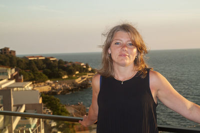 Portrait of woman standing against sea against sky