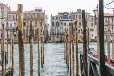 Wooden poles in river against buildings