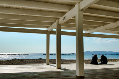 People relaxing on beach by sea against sky