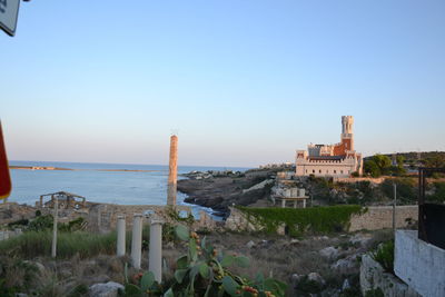 Buildings by sea against clear sky