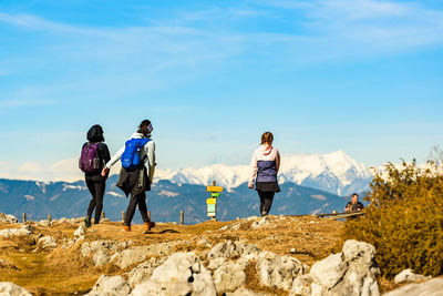 Rear view of people walking on mountain against sky