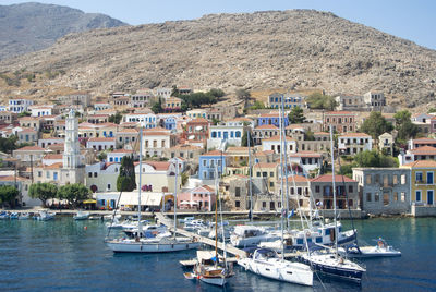 Sailboats moored on harbor by buildings in city