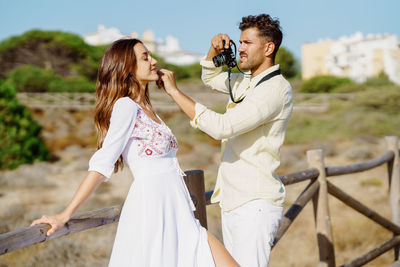 Man photographing woman standing on land