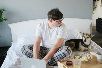 Young woman using laptop while sitting on bed at home