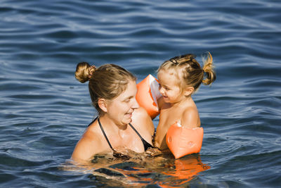 Rear view of mother and daughter in water