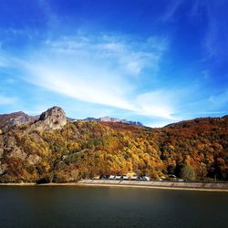 Scenic view of lake by mountain against blue sky