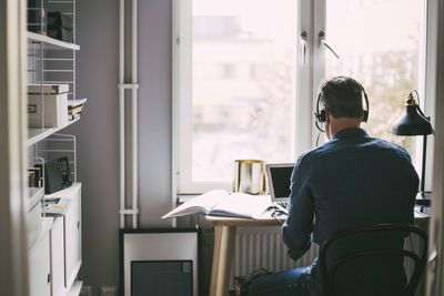 Rear view of man in office at home with headphones