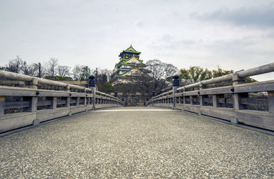 View of footbridge amidst buildings against sky