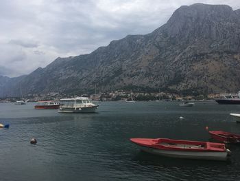 Sailboats moored on sea by mountains against sky