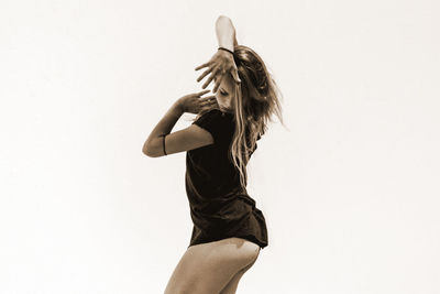 Young woman dancing against white background