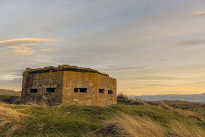 Old building on field against sky during sunset