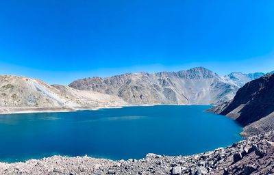 Scenic view of lake and mountains against clear blue sky