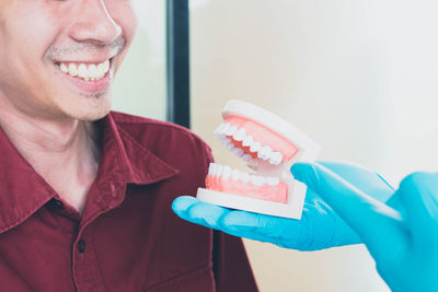 Cropped hands showing dentures to patient