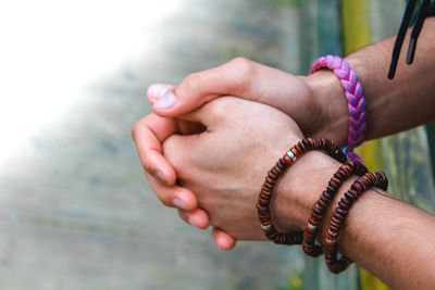 Cropped image of person with hands clasped wearing bracelets