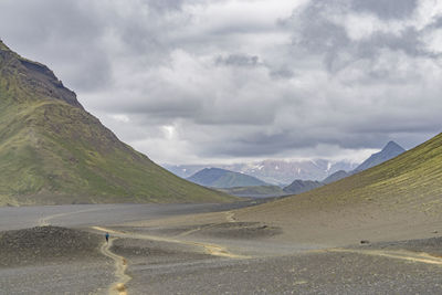 Scenic view of road by mountains against sky