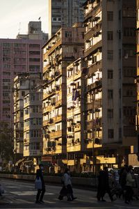 People crossing the road by buildings in city in the evening