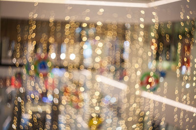 Defocused image of illuminated lights on wet street at night