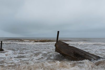 Rock in sea against sky