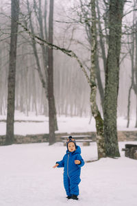 Boy standing on snow covered field during winter