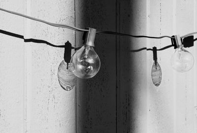 Close-up of light bulb hanging against wall