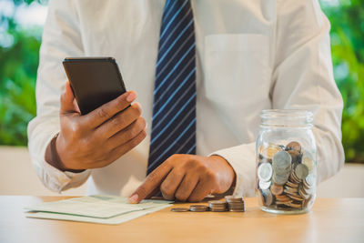 Midsection of man using smart phone on table