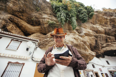 Low angle view of man using mobile phone while standing against mountain