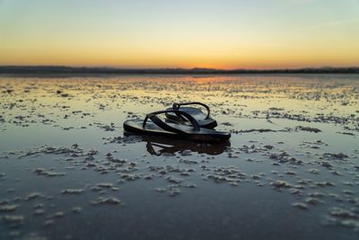 Boat on shore at beach against sky during sunset