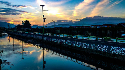 Scenic view of road by river against sky during sunset