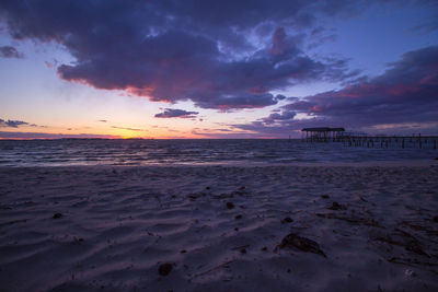 Scenic view of beach against sky at sunset