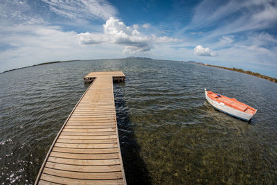 Fish-eye view of jetty in sea against sky