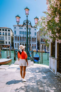 Rear view of woman walking on street by building