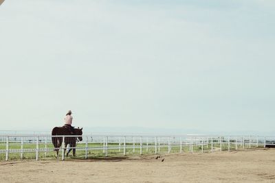 Woman on pier at beach against clear sky