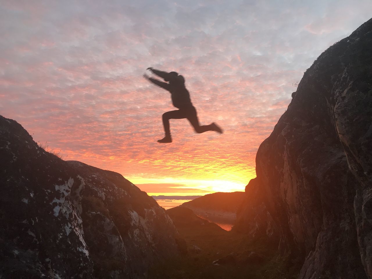 sunset, sky, silhouette, beauty in nature, mountain, rock, rock - object, orange color, solid, tranquil scene, one person, nature, real people, leisure activity, cloud - sky, scenics - nature, tranquility, rock formation, adventure, mountain range, sun, outdoors