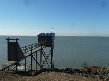 Lifeguard hut on beach against clear blue sky