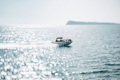 Boat sailing on sea against clear sky