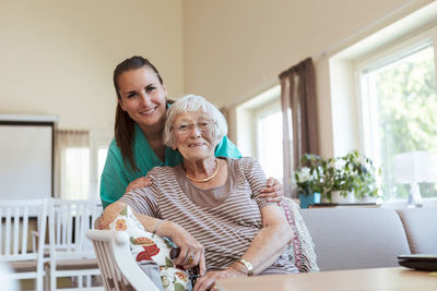 Portrait of smiling senior woman and healthcare worker at nursing home