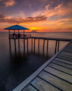 Pier over sea against sky during sunset