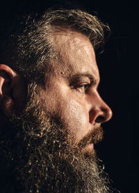 Close-up of man looking away against black background