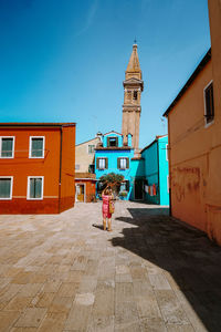 Woman on footpath amidst buildings in city