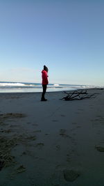 Woman standing on beach against clear sky