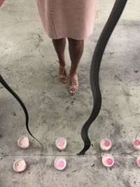 Low section of woman standing on pink shoes