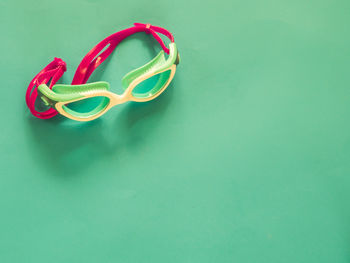 High angle view of swimming goggles against green background